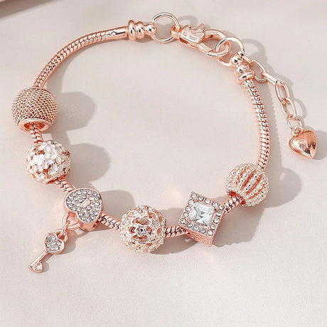 Rose gold bracelet with various charms on a light background