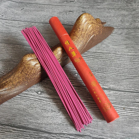 Red incense stick and pink incense sticks on a wooden surface