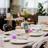 Dining table set with tea cups, a bottle of Sipsmith gin, and floral arrangement.