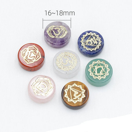 Set of seven crystal stones with chakra symbols on a white background