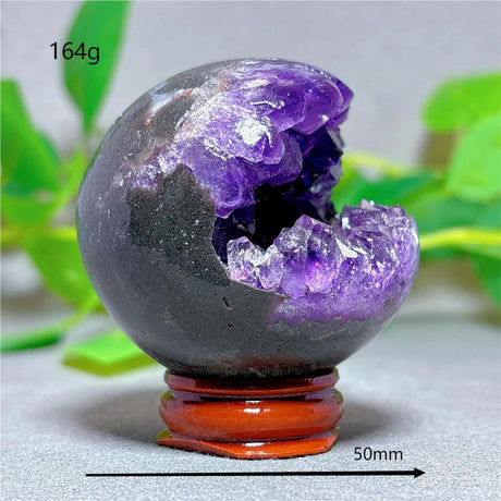 Amethyst geode on a wooden stand with a blurred green plant background