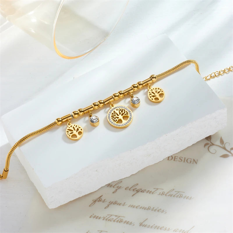 Gold bracelet with tree of life charms on a white surface
