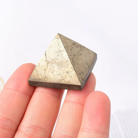 Pyramidal stone held between fingers against a white background