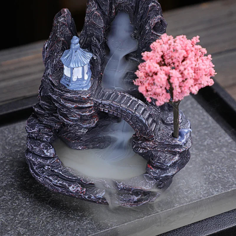 Decorative stone arch with cherry blossom tree and pagoda on a dark surface