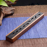 Wooden incense holder with decorative patterns on a blue mat