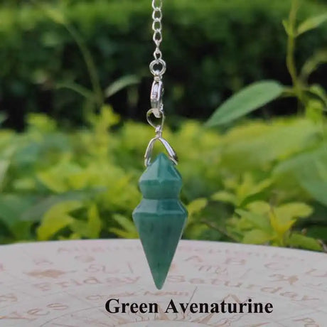Green aventurine crystal pendant on a chain with a blurred green leafy background
