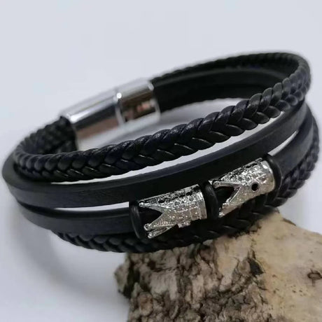 Black braided leather bracelet with silver charms on a light gray background