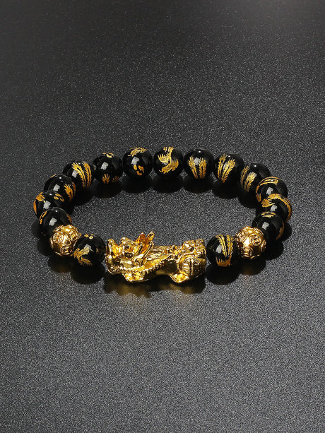 Black beaded bracelet with gold accents and a large gold dragon charm on a dark background