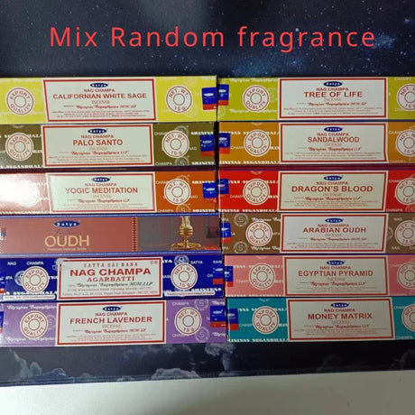 Stack of Nag Champa incense boxes with various fragrances on a dark background.