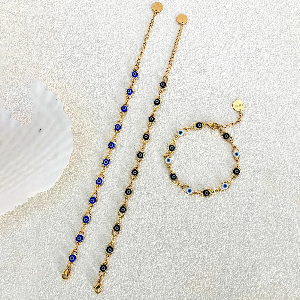 Gold necklace and bracelet with blue and black beads on a textured white surface
