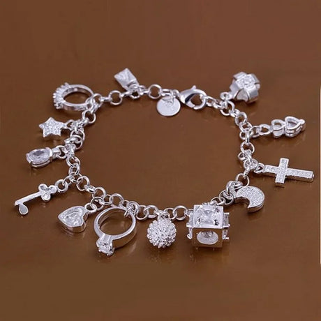 Silver charm bracelet with various charms on a brown background