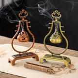 Two incense burners, one gold and one bronze, on a dark background with smoke.