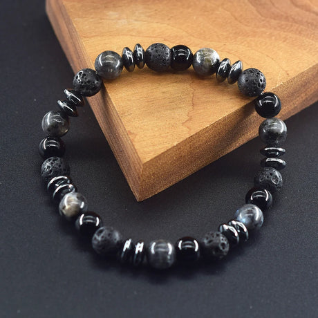 Black and gray beaded bracelet on a dark surface with a wooden block