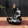 Black ceramic incense burner with incense sticks on a dark background
