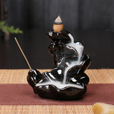 Black ceramic incense burner with incense sticks on a dark background