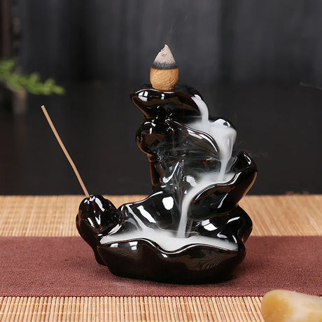 Black ceramic incense burner with incense sticks on a dark background