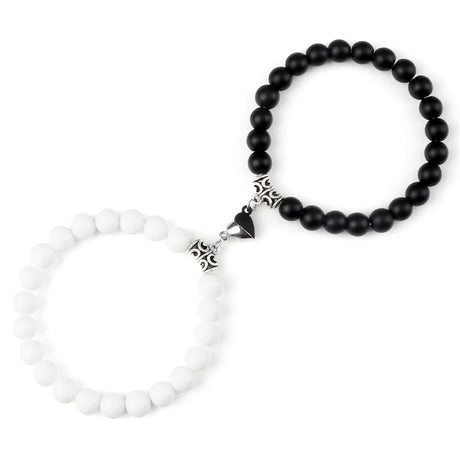 Two bracelets, one with black beads and a silver clasp, the other with white beads and a similar clasp, on a white background.