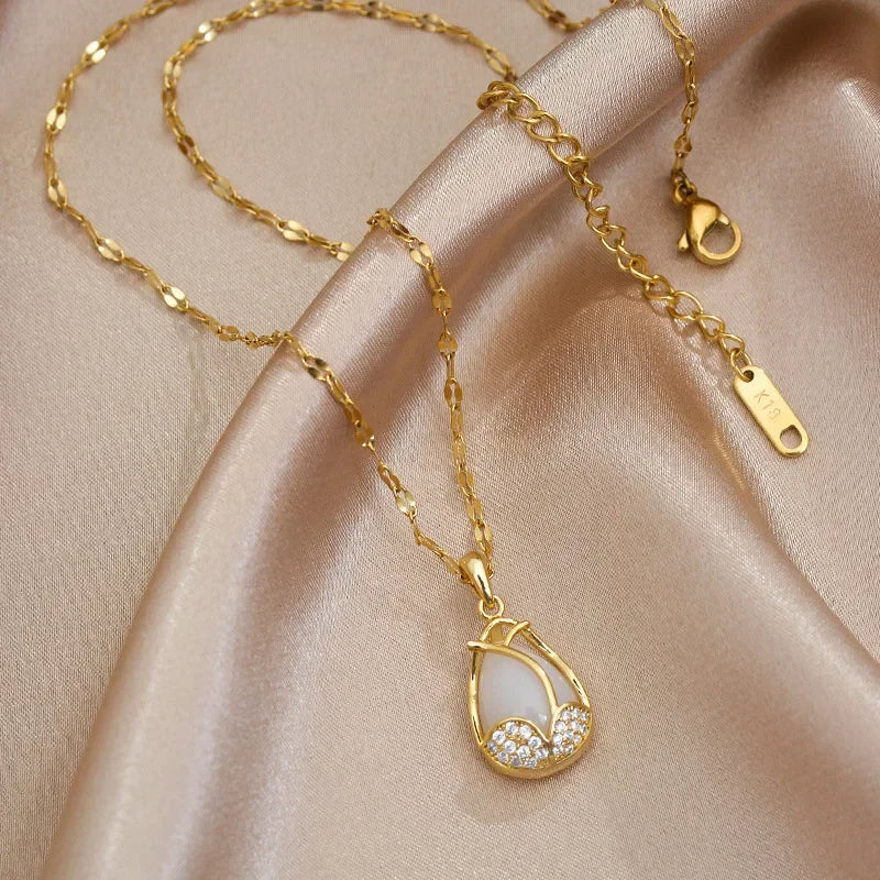 Gold necklace with a teardrop pendant on a beige fabric background