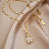 Gold necklace with a teardrop pendant on a beige fabric background