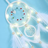 White dreamcatcher with feathers and lights on a light blue background
