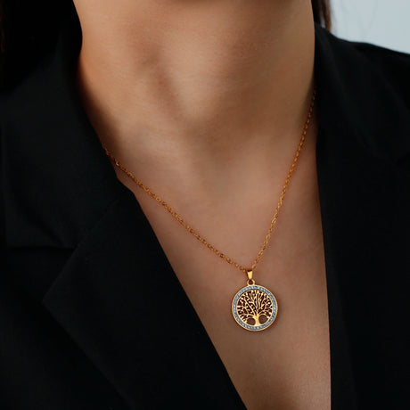 Gold necklace with a tree-of-life pendant on a person wearing a black shirt.