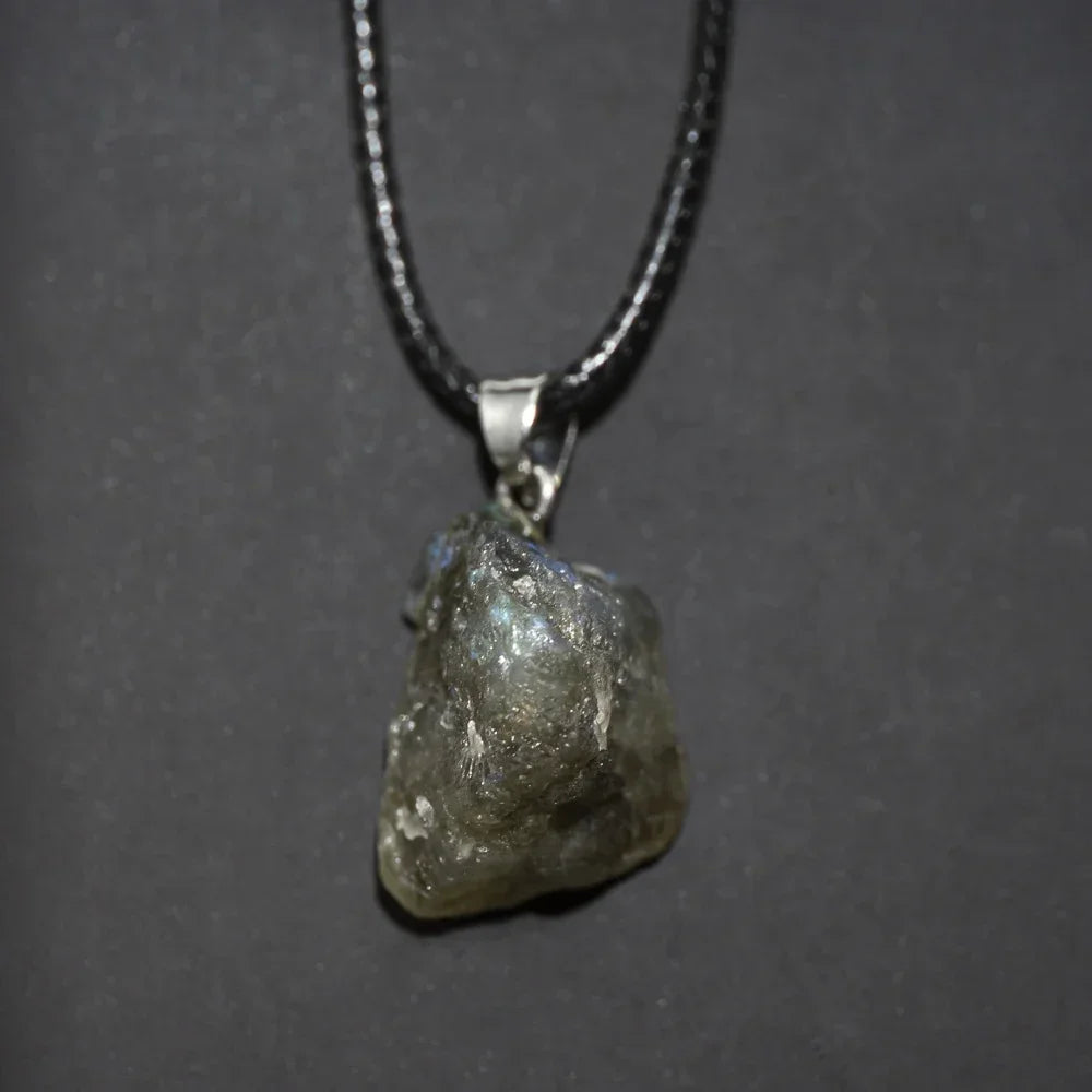 Raw diamond pendant on a chain against a dark background
