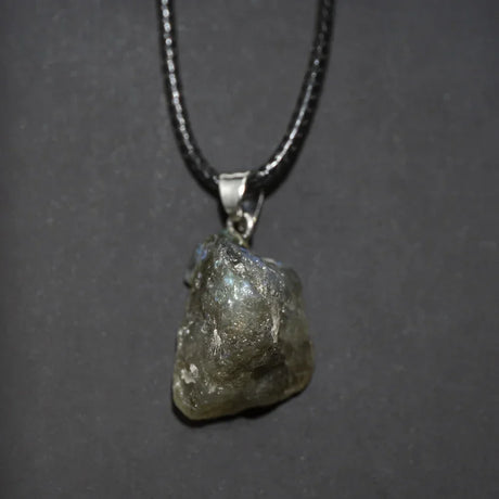 Raw diamond pendant on a chain against a dark background