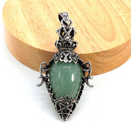 Green stone pendant with silver decorative elements on a wooden block