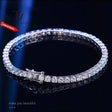 Silver bracelet with clear stones on a dark background, branded 'TJ'.