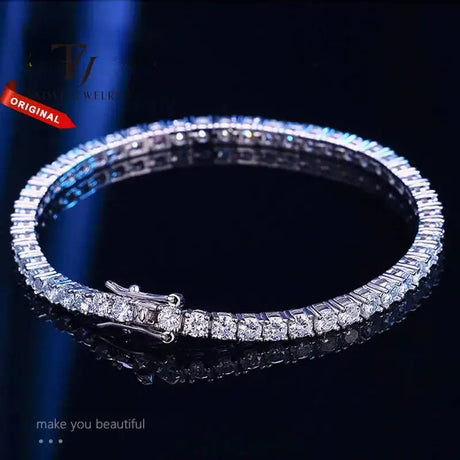 Silver bracelet with clear stones on a dark background, branded 'TJ'.