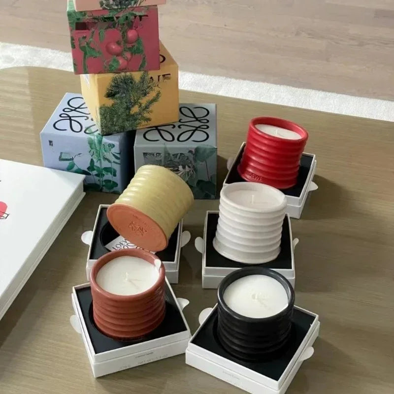 Collection of various candles in different containers on a wooden surface.