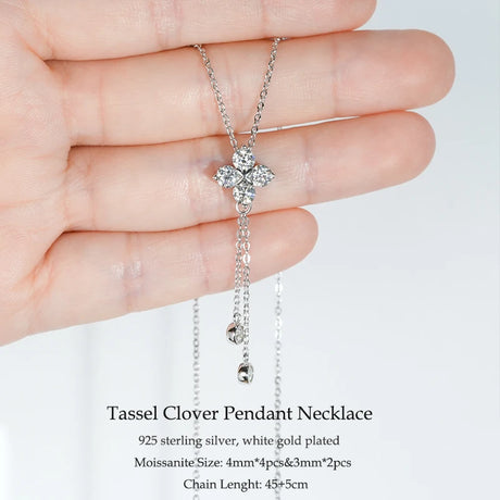 Silver tassel clover pendant necklace held in a hand with product details on a white background