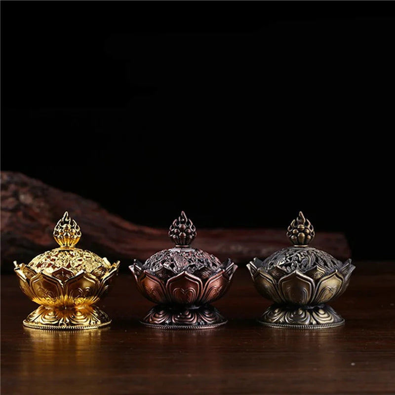 Three ornate incense holders in gold, silver, and bronze on a dark background