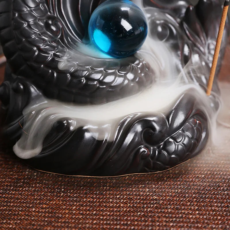 Decorative incense burner with blue sphere and incense stick on a textured surface