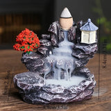 Decorative water fountain with rocks, trees, and a pagoda on a wooden surface.