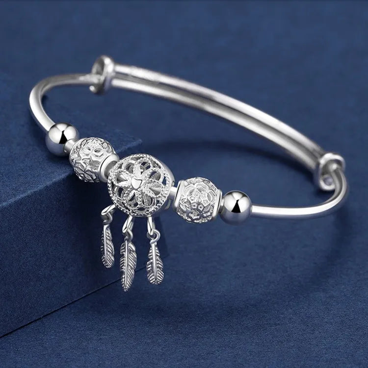 Silver bracelet with decorative beads and charms on a blue background