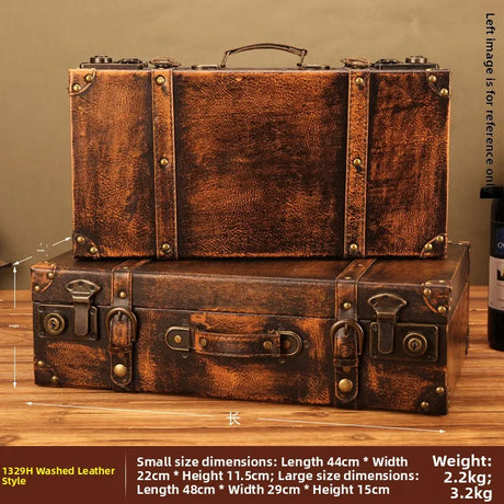 Two vintage-style leather suitcases stacked on a wooden surface with a bottle of wine in the background.