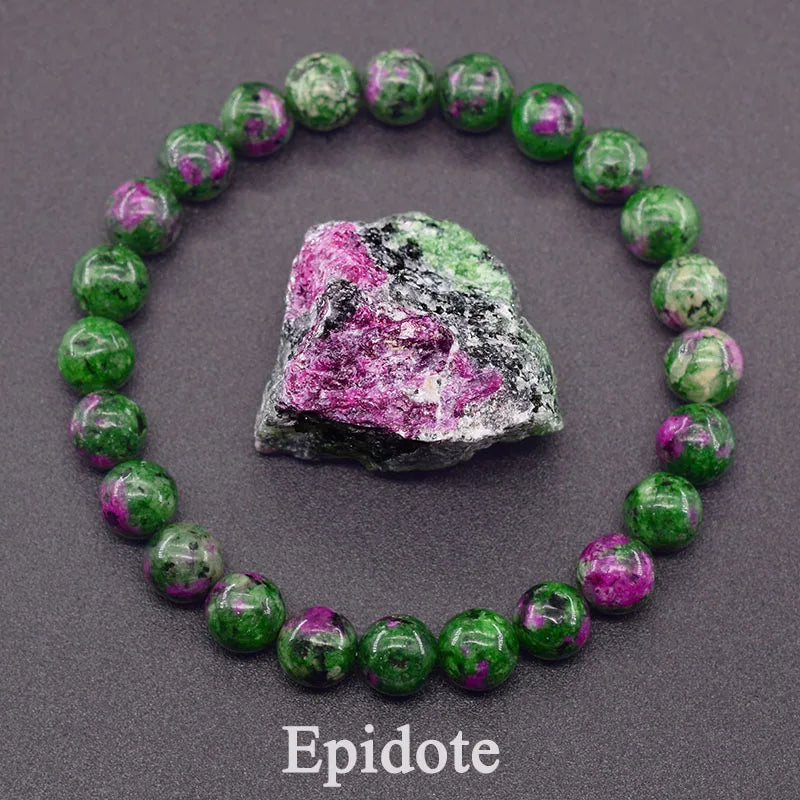 Green and pink bead bracelet with a piece of epidote crystal on a gray background