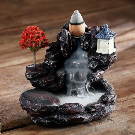 Decorative incense burner with rocks, tree, and lantern on a wooden surface