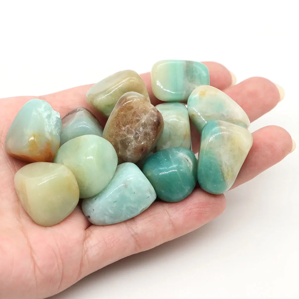 Hand holding a collection of green and brown stones against a white background