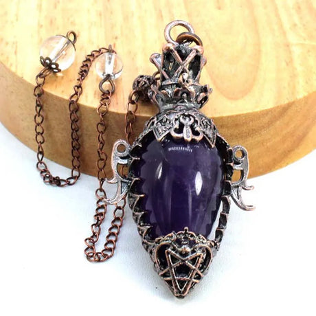 Purple pendant with intricate metalwork on a wooden surface
