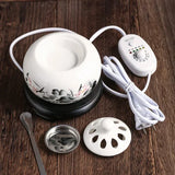 White ceramic warmer with control panel, lid, and spoon on a wooden surface