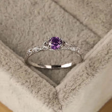 Silver ring with a purple gemstone in a soft fabric box
