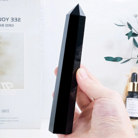 Hand holding a black crystal-like object with a blurred background