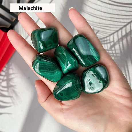 Hand holding green malachite stones with a blurred background