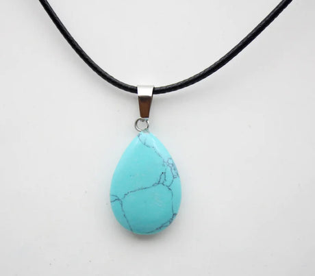 Turquoise teardrop pendant on a black cord against a white background