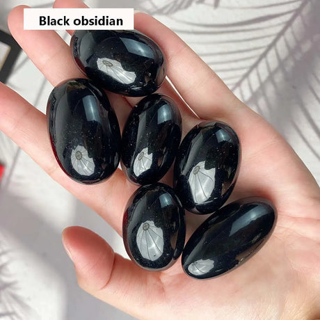 Hand holding black obsidian stones with a blurred natural background