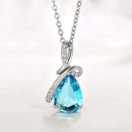 Silver necklace with a blue teardrop pendant on a light background
