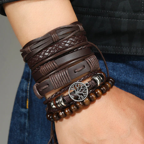Multiple brown leather bracelets with a tree of life charm on a wrist against a neutral background.