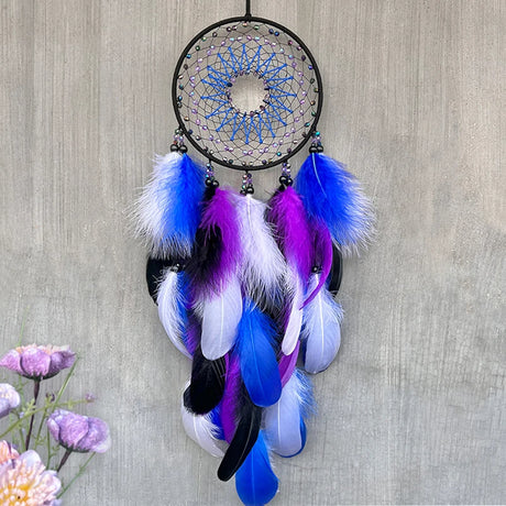 Dreamcatcher with blue, purple, and white feathers on a wooden background